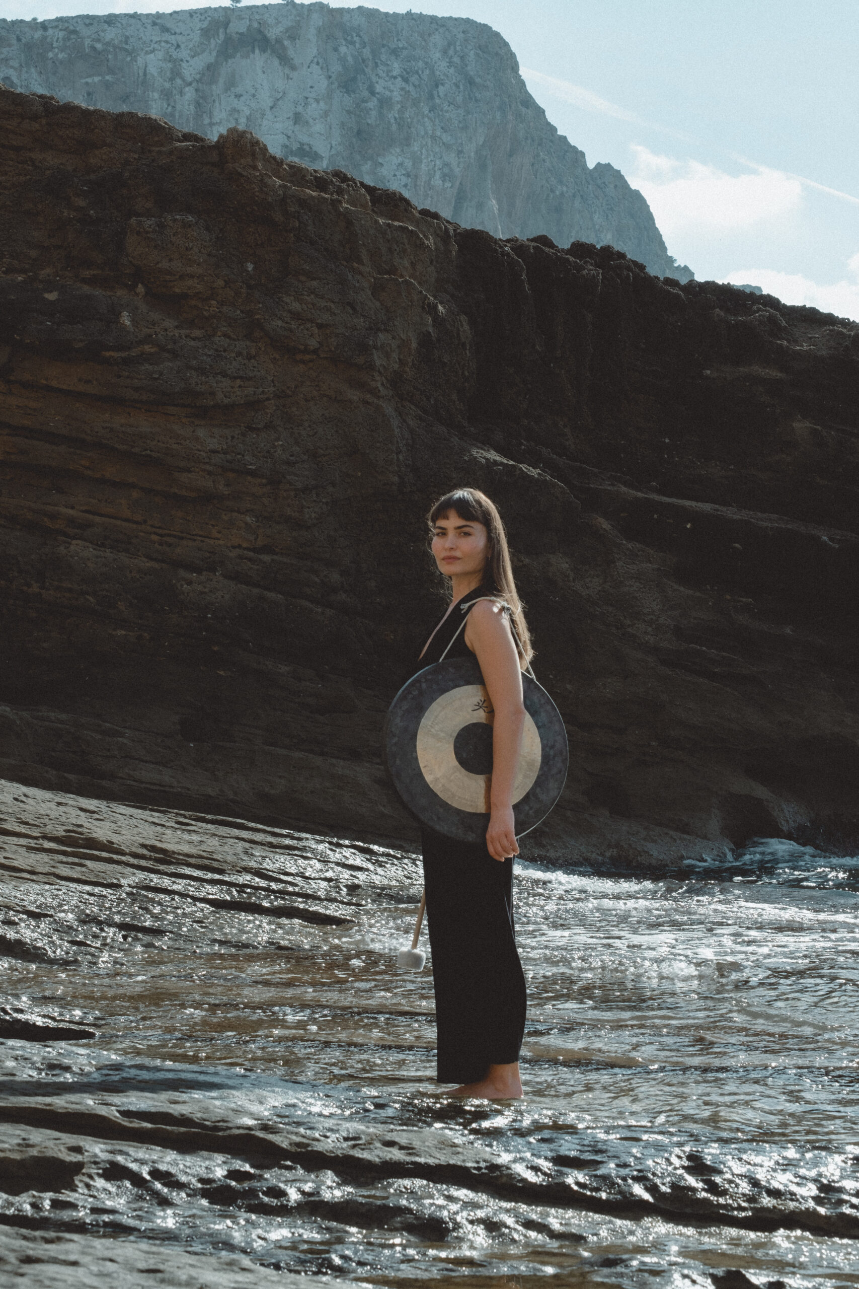 Sedef holding a gong beside the sea